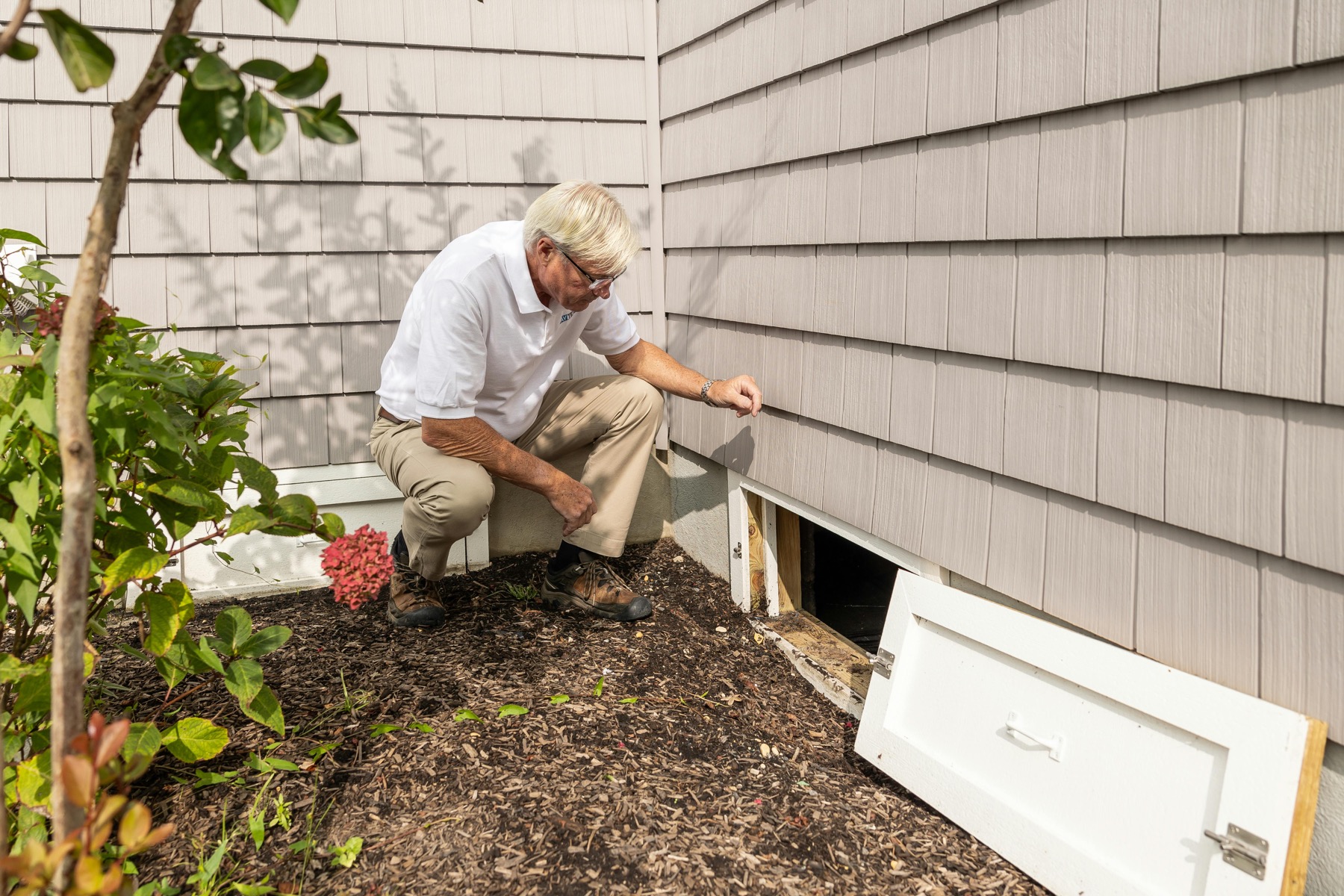 Technician inspecting a crawl space entrance for moisture concerns
